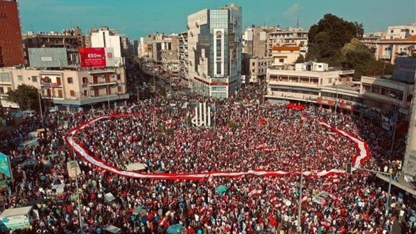 سُكّان مدينة طرابلس والمناطق المُجاورة يحتشدُونَ في ساحة النّور، ويرفعون الأعلام اللّبنانيّة على وقعِ النّشيد الوطني اللّبناني والأغاني الوطنيّة، المجموعة اللّبنانيّة للإرسال ، ۲۰ تشرين الأوّل ۲۰۱۹